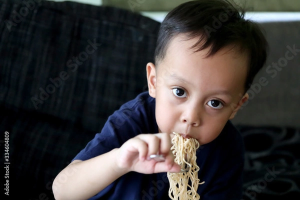 Obraz Little child boy eating Instant noodles.