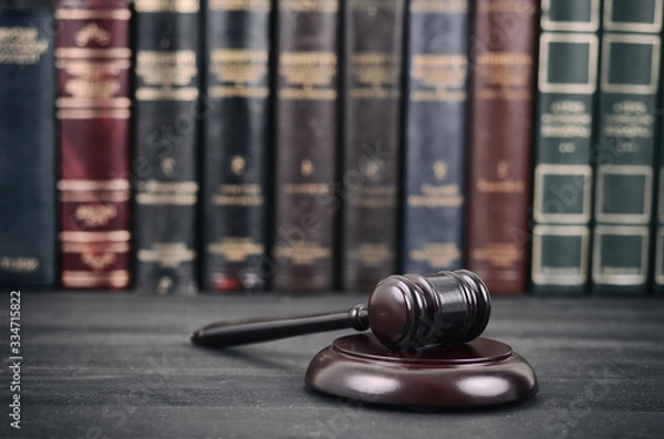 Fototapeta  Judge Gavel on a black wooden background in front of a law library.