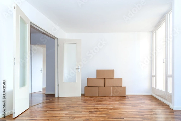 Fototapeta Umzugskartons in einer leeren Wohnung mit weißen Wänden