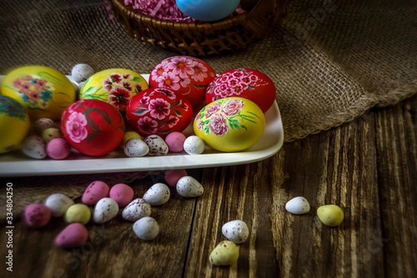 Fototapeta Easter composition on a wooden background. Hand painting Easter eggs. The concept of religious holidays, family traditions. Selective focus.