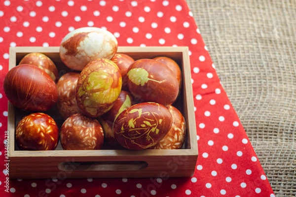 Fototapeta Chicken eggs colored with old-fashioned natural method by onion husks. Brown eggs with different natural patterns in box on red. Selective focus with copyspace. Traditional Easter and Spring concept