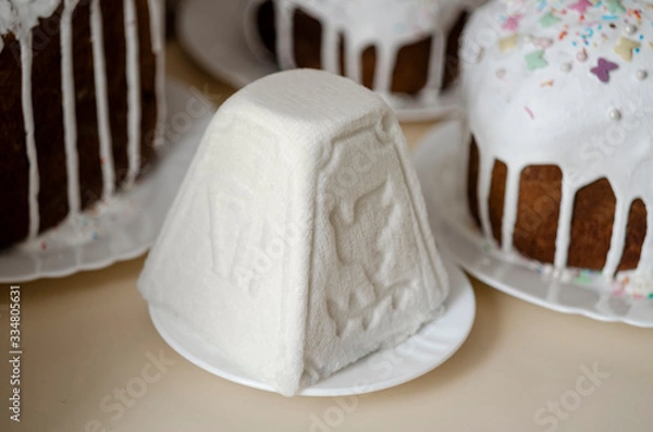 Fototapeta Traditional Russian and Ukrainian Easter cottage cheese dessert in rustic style. Orthodox Paskha in ceramic plate on table with kulich cakes. Still life with curd pyramid and sweet bread in spring day