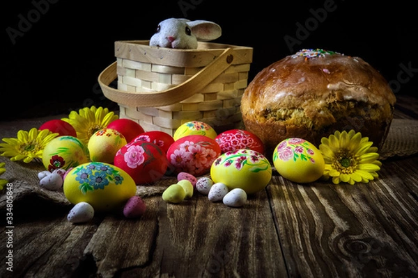 Fototapeta Traditional holiday composition. Hand painting Easter eggs with orthodox sweet bread on a dark wooden table. With rabbit figure. Selective focus.