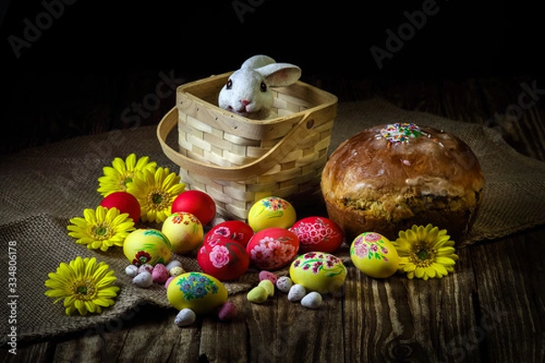 Fototapeta Traditional holiday composition. Hand painting Easter eggs with orthodox sweet bread on a dark wooden table. With rabbit figure. Selective focus.