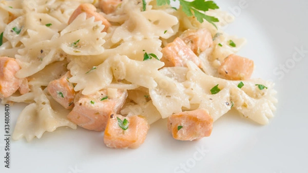 Fototapeta fried salmon chops and farfalle pasta with cream sauce decorated with parsley