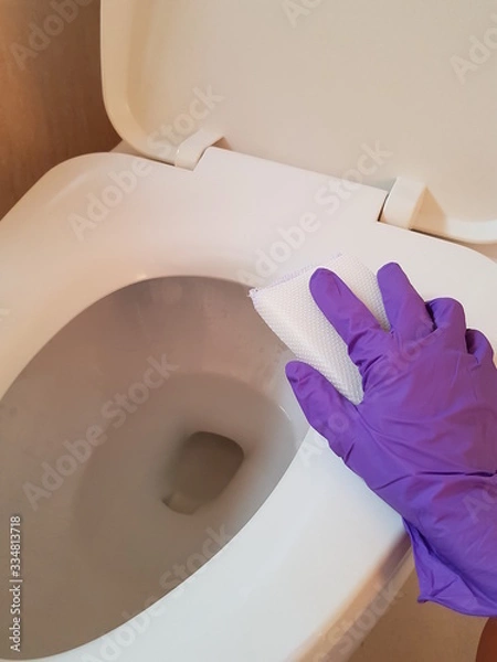 Obraz Closeup of lady wearing glove using sponge to clean toilet.  Hygiene concept.