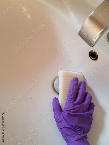 Obraz Closeup of lady wearing glove using sponge to wash sink.  Hygiene concept.