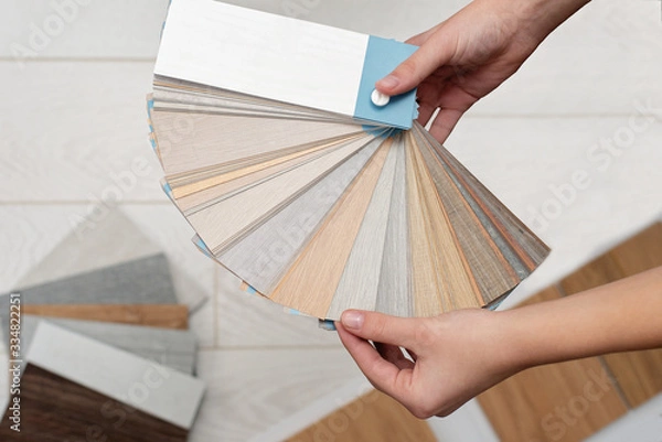 Fototapeta Designer architect holds a palette of textures and decor for a wooden floor made of laminate and vinyl. Interior Design. Planning for repairs and home construction.