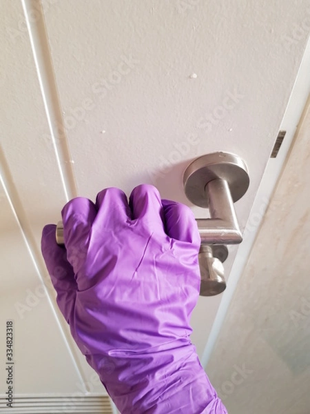 Obraz Closeup of lady wearing glove to open door.  Prevention of Coronavirus Covid-19 concept.