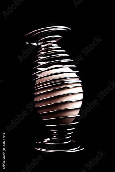 Obraz white egg in two egg holders spiral shaped on black background