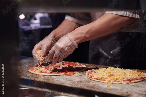 Fototapeta Man making pizza at the kitchen. Ingredients for Italian pizza. Gloved hands.