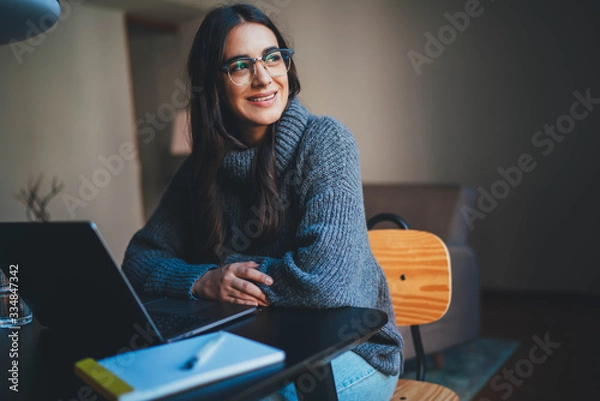 Obraz Young female entrepreneur in trendy eyeglasses sitting at modern office using laptop computer working on new Sustainable development project, Businesswoman working from home office