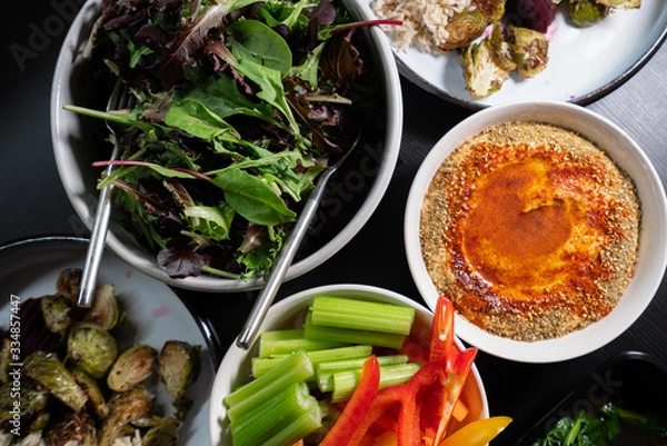 Obraz Healthy Green food such as peppers, celery, lettuce and hummus served on a dark table. Health and clean eating.