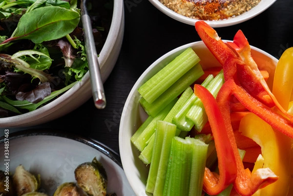 Obraz Healthy Green food such as peppers, celery, lettuce and hummus served on a dark table. Health and clean eating.