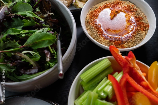Obraz Healthy Green food such as peppers, celery, lettuce and hummus served on a dark table. Health and clean eating.