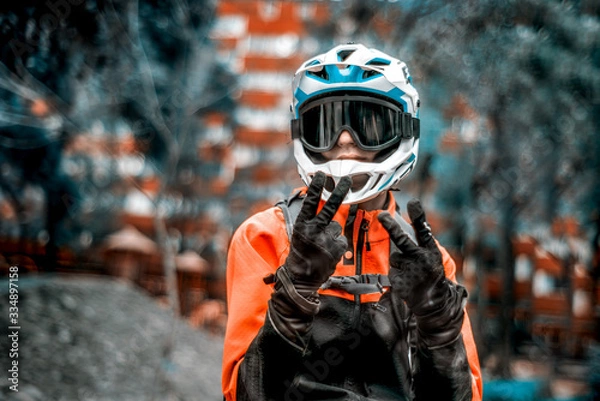 Fototapeta Joven latino con casco y guantes, deportista en bici saludando en un parque al aire libre