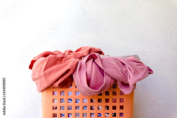 Fototapeta Clothes that have already been worn and placed in a basket are waiting to be washed, with the main scene being white.