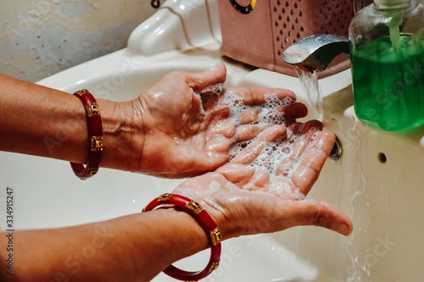 Obraz Closeup shot of Hands of an Indian female wearing bangles washing her hands after applying hand sanitizer