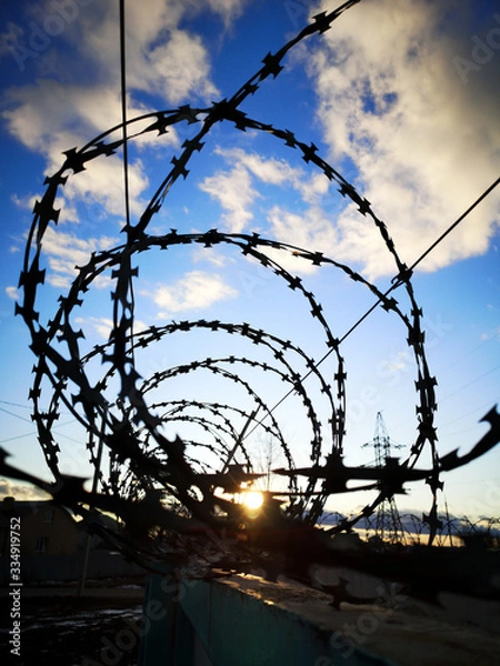 Obraz Barbed wire against the sky with clouds