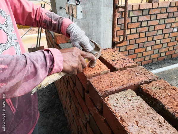 Obraz construction worker laying bricks at constrction site.