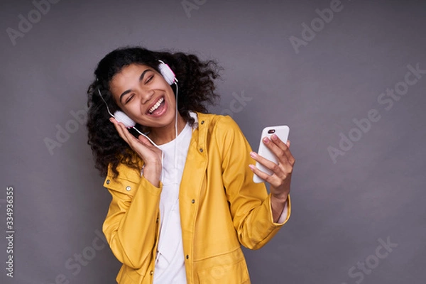 Obraz Funny girl dark-skinned listens to music with headphones.