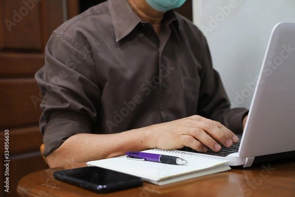 Fototapeta Closeup of man's hand doing his work with notebook computer at home during COVID-19 outbreak around the world. 