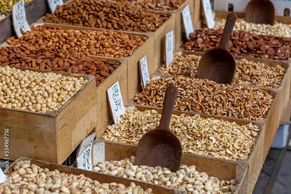 Obraz Variety of nuts in tray at food market, shallow depth of field, selective focus on almonds, blurred cashew nuts and pistachio on foreground, blurred nuts on background