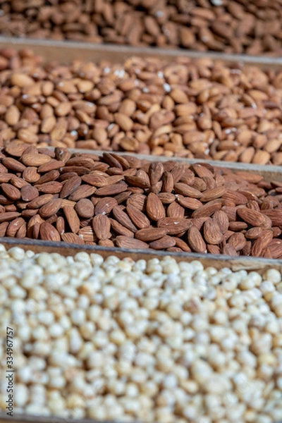 Obraz Variety of nuts closeup in tray marketplace, selective focus on almonds, blurred hazelnuts on foreground, blurred peanuts on background