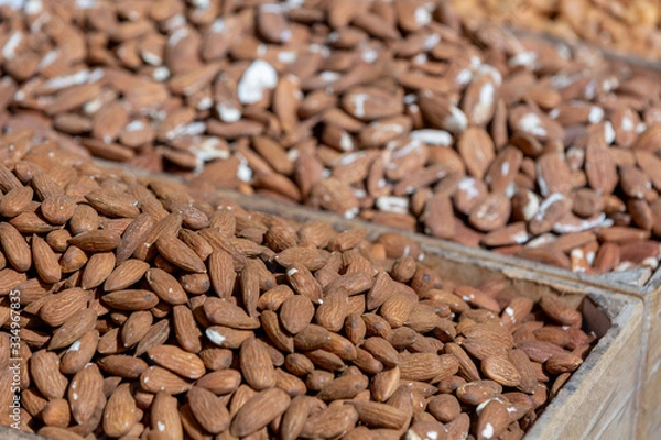 Obraz Clump of almond in tray on sunlight at food market, selective focus on foreground, blurred nuts on background