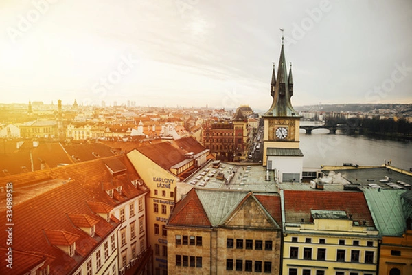Fototapeta Vltava river and clock tower over looking the city taken during sunset hours in Prague, Czech republic. Old Town Water Tower, or Staromestska vodarna with tower clock on Vltava bank.