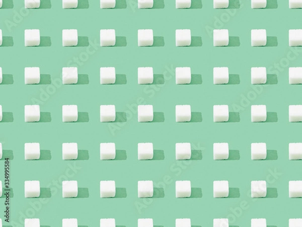 Obraz top view of lump sugar on green, seamless background pattern