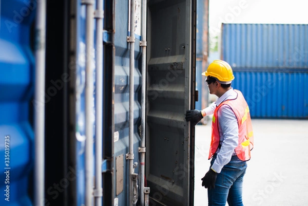 Fototapeta Young Asian man worker foreman open the door of shipping Containers at commercial shipping dock felling serious. Engineer inspection. Cargo freight ship import export concept.