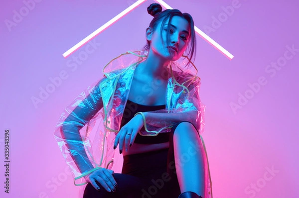 Fototapeta Elegant beautiful woman in a raincoat around colourful bright neon