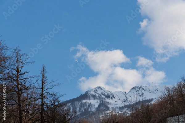 Fototapeta Peaks of snow-capped mountains against the blue sky with clouds