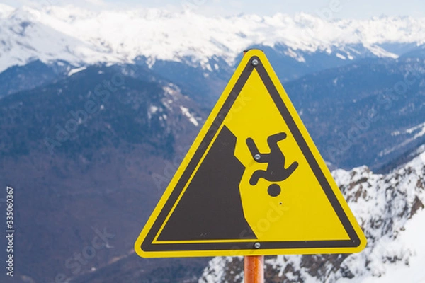 Fototapeta warning sign of a fall from a mountain against a blue sky