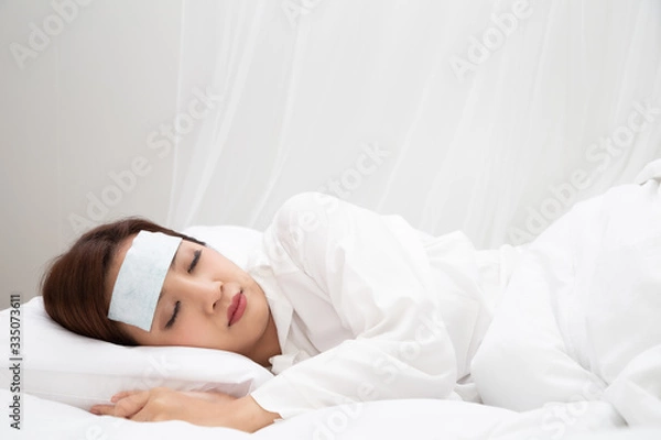 Fototapeta Young Asian woman with high fever while sleeping on white bed at home, Sick symptoms include fever, coughing and sore throat or ill due to infection bacteria or virus