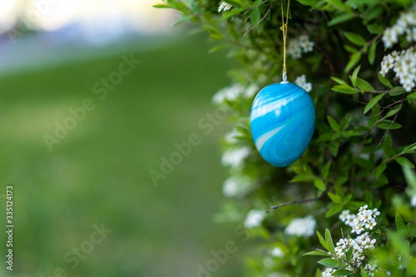 Fototapeta Blue plastic easter egg decoration spirea shrub easter