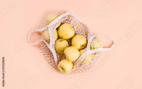 Fototapeta Ripe apples of different varieties in an eco bag on a light background.