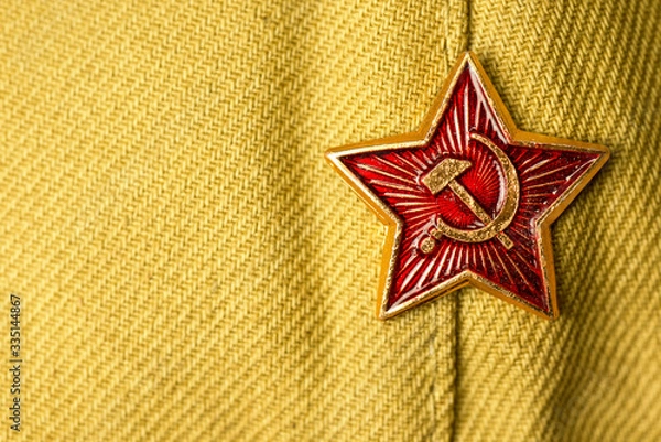Fototapeta Old soviet military badge with hammer and sickle on light green cloth headgear. Red five-pointed soviet  communist gold red star. Symbol of the USSR. Space for the text. Victory Day Concept.