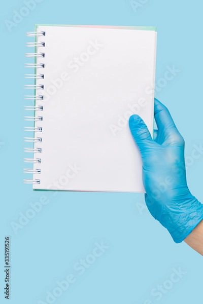 Fototapeta female hand in a  medical glove holds a blank form of paper on a blue background. Mock up, business card
