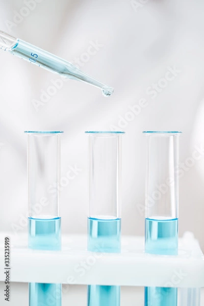 Fototapeta clean glass tubes and pipette with light blue reagent for coronavirus test in modern laboratory extreme closeup