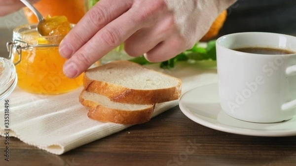 Obraz Tasty and hearty breakfast jam on crisp bread. Man makes a sandwich. Close up.