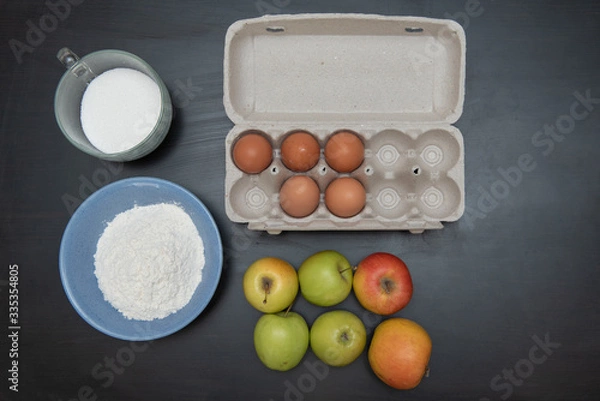 Fototapeta Products for the pie on the table. Eggs in a box, apples, flour in a bowl, sugar in a glass