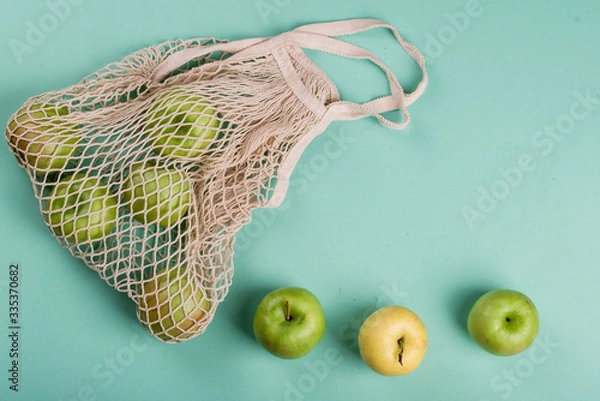 Fototapeta Ripe apples of different varieties in an eco bag on a light background.