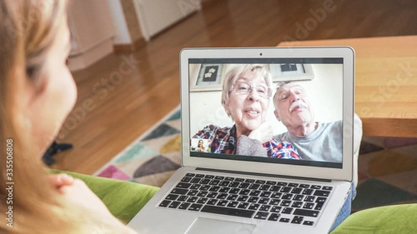 Fototapeta Daughter having a facetime video call with her elders. Family video chatting at home. Self isolation, modern technology connecting people of all ages concept.