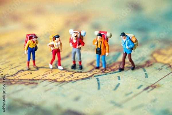Fototapeta Miniature people: Group of backpacker on vintage world map using as business trip traveler adviser agency or explorer on earth background concept.