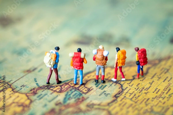 Fototapeta Miniature people: Group of backpacker on vintage world map using as business trip traveler adviser agency or explorer on earth background concept.