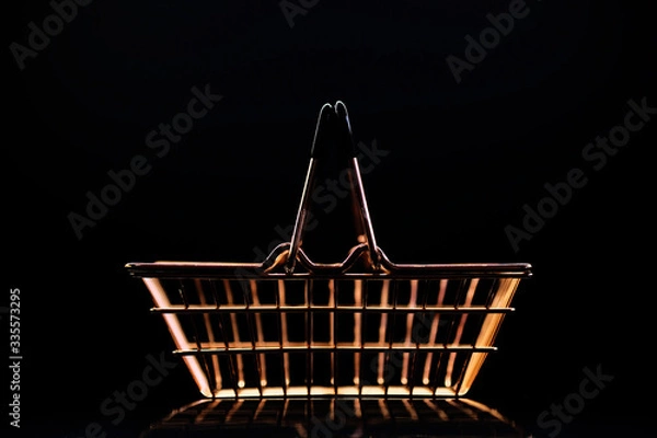 Obraz golden metal basket for a grocery store on a dark background with reflection