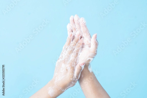 Obraz Closeup woman's hand washing with soap on blue background, health care concept