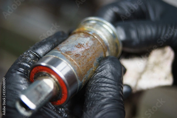 Fototapeta Mechanic or serviceman installing wheel on a bicycle in workshop